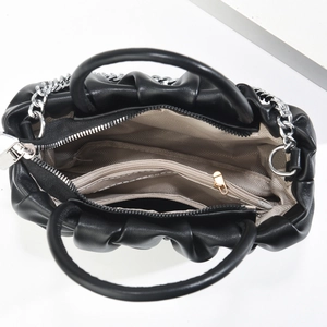 Macro view of black pleated cloud bag interior showing compartments and silver chain
