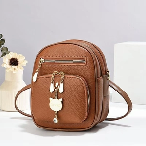 Brown lychee leather mini backpack with golden cat charm and dual zipper pockets