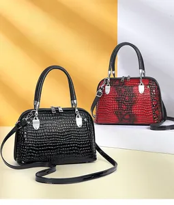 Detail of shell-shaped handbags in black and gradient red faux snakeskin leather texture