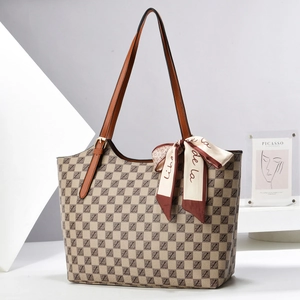 Detail of checkered tote bag featuring brown leather straps and decorative silk scarf