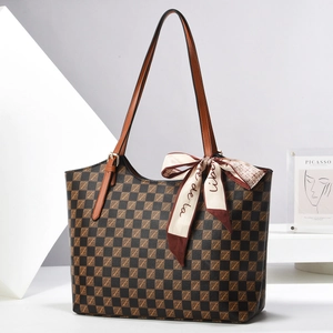 Detailed view of checkered tote bag with brown leather straps and stylish silk scarf detail