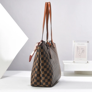 Detail of checkered tote bag with brown leather handles and decorative floral scarf