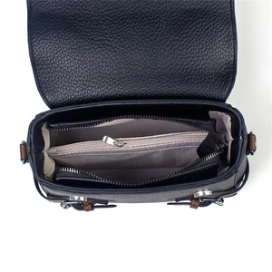 Detailed interior of a black pebble leather crossbody bag with a zipped central compartment