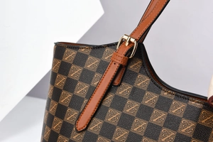 Detail of checkered tote bag with Z-pattern leather trim and adjustable gold buckle