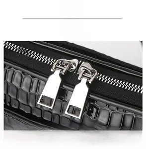 Close-up of dual silver metal zippers on high-gloss black croc-embossed shell bag