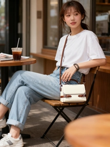 Detail of elegant beige square handbag with brown trim in a cafe outdoor setting