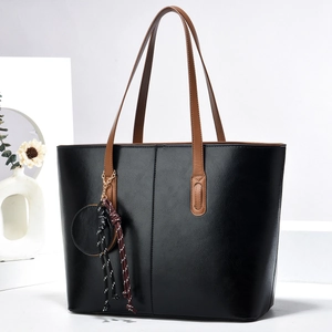 Grand sac cabas noir minimaliste avec poignées marron et petit accessoire rond décoratif