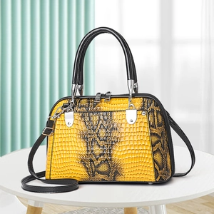 Elegant yellow snakeskin shell handbag with black top handles and detachable crossbody strap