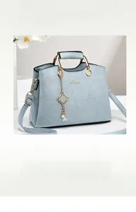 Detail of mint green tote bag with geometric stitching and gold chain tassel charm