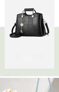 Detail of black geometric pattern leather bag with gold handles and decorative tassel
