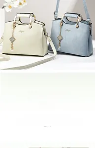 Detail of stone textured geometric handbag with metal handle and decorative pearl charm