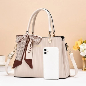 Detail of beige tote bag with pleated texture, silk scarf decoration and metal hardware