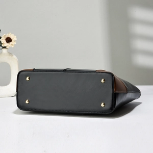 Detailed view of tote bag bottom with protective gold metal studs and two-tone leather finish