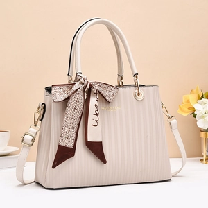 Detail of cream white textured handbag with elegant silk scarf and gold lettering