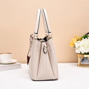 Detail of pleated beige tote bag with a silk scarf tied on the handle for elegant styling