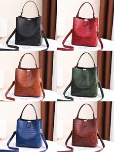 Detail view of crocodile pattern bucket bags in black, red, brown, and green colors