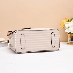 Detail view of beige handbag base featuring anti-wear pads and textured stripes