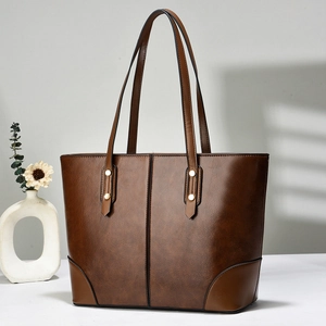 Detail view of vintage brown leather tote bag with gold rivets and reinforced stitching
