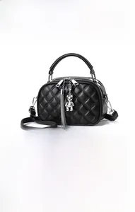 Detail of black quilted crossbody bag featuring silver bear charm and metal tassels