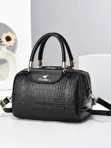 Detailed close-up of glossy black crocodile embossed leather with gold hardware and logo