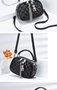 Detail of black quilted crossbody bag featuring silver charms and dual zipper texture