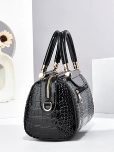Macro detail of glossy black crocodile pattern handbag with gold metal hardware