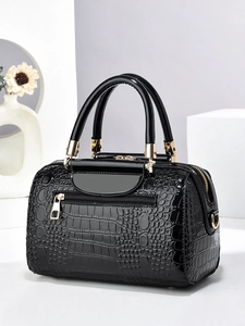 Detail of black crocodile embossed patent leather Boston bag with gold hardware