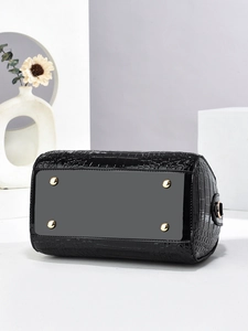 Detail of glossy crocodile pattern handbag base with protective gold metal feet studs