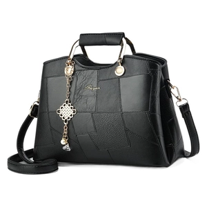 Black leather handbag with stone texture patchwork, metal handle, and tassel accessory