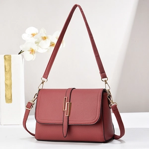 Elegant reddish-brown lychee leather crossbody bag with golden rectangular metal buckle
