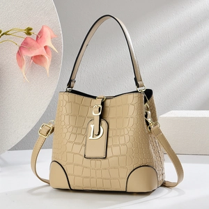 Elegant beige crocodile pattern bucket bag with golden D-pendant and adjustable strap