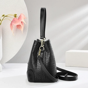 Detail of black crocodile pattern bucket bag with golden hardware and stylish handle