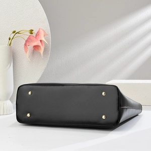 Dettaglio del fondo della borsa tote in pelle nera con quattro piedini in metallo dorato