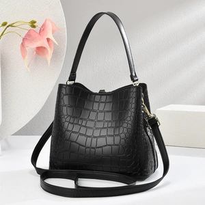 Detail view of black crocodile pattern handbag with golden hardware and shoulder strap