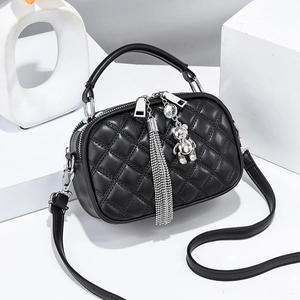 Black quilted crossbody bag with silver bear charm and fringe detail on white background