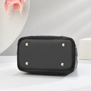 Detail of black crocodile-embossed bucket bag base with protective gold metal feet