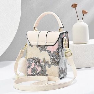 Dettaglio borsa a tracolla bianco panna con stampe floreali paisley e ciondolo morbido