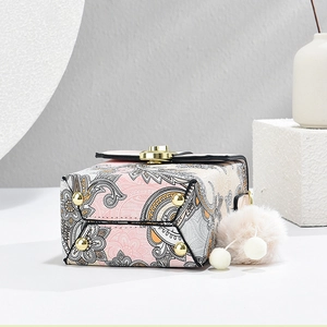 Dettaglio borsa paisley con piedini protettivi in metallo dorato e ciondolo di pelliccia