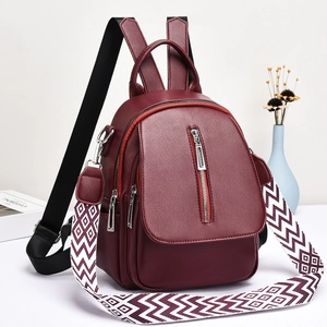 Détail d'un sac à dos bordeaux en cuir avec une large bandoulière à motifs géométriques