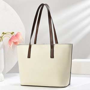 Dettaglio della borsa tote crema con manici marroni su un piedistallo decorativo