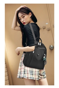 Détail du sac à dos de voyage noir en tissu Oxford avec logo V en métal et pendentif
