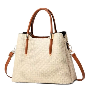 Beige woven handbag with brown leather straps and gold hardware on white background