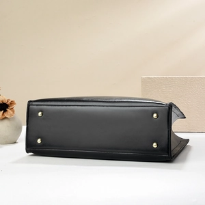 Detail view of the black leather tote bag bottom with four protective gold metal feet