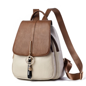 Detail of two-tone PU leather backpack featuring metal smiley charm and ribbon accent