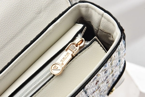 Macro shot of white lychee leather and colorful tweed fabric with golden MUWK hardware