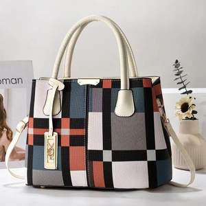 Grand sac cabas en toile rayée aux couleurs contrastées avec poignées en cuir sur table