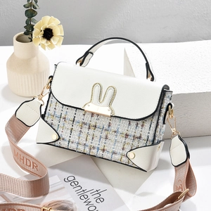 Detail of tweed拼接handbag featuring a golden rabbit ear clasp and wide logo strap