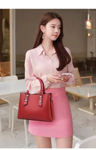 Detailed view of red textured leather handbag with dual handles in a lifestyle setting