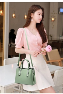 Detailed view of sage green pebbled leather handbag with adjustable strap on a female model