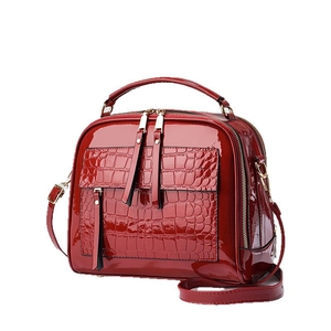 Glossy burgundy patent leather handbag with crocodile pattern panels and top handles